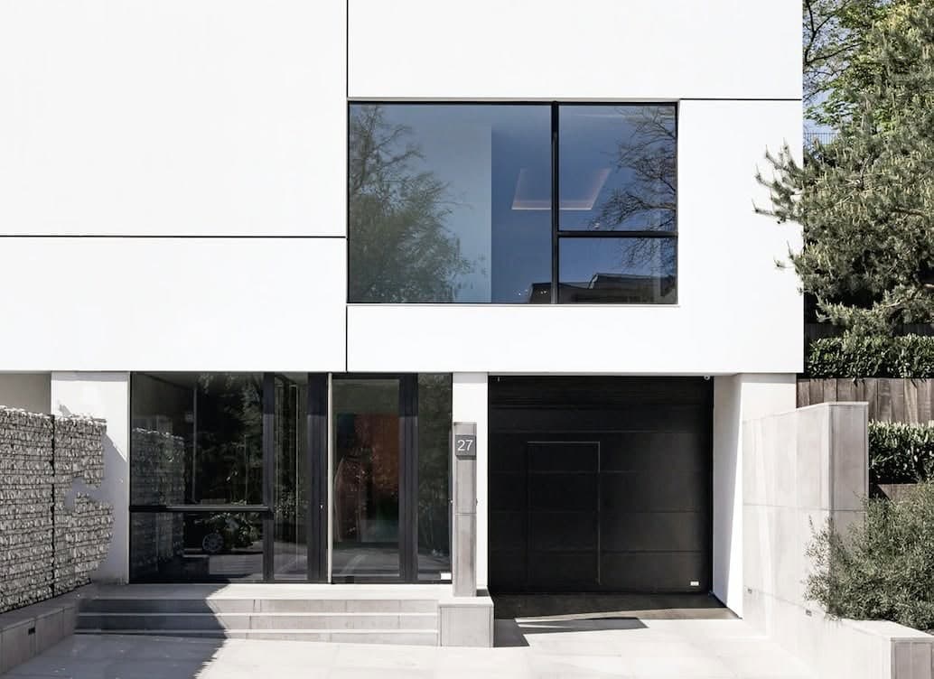 Menuiseries en aluminium noir posées par COREMI : entrée vitrée toute hauteur et porte de garage sectionnelle.